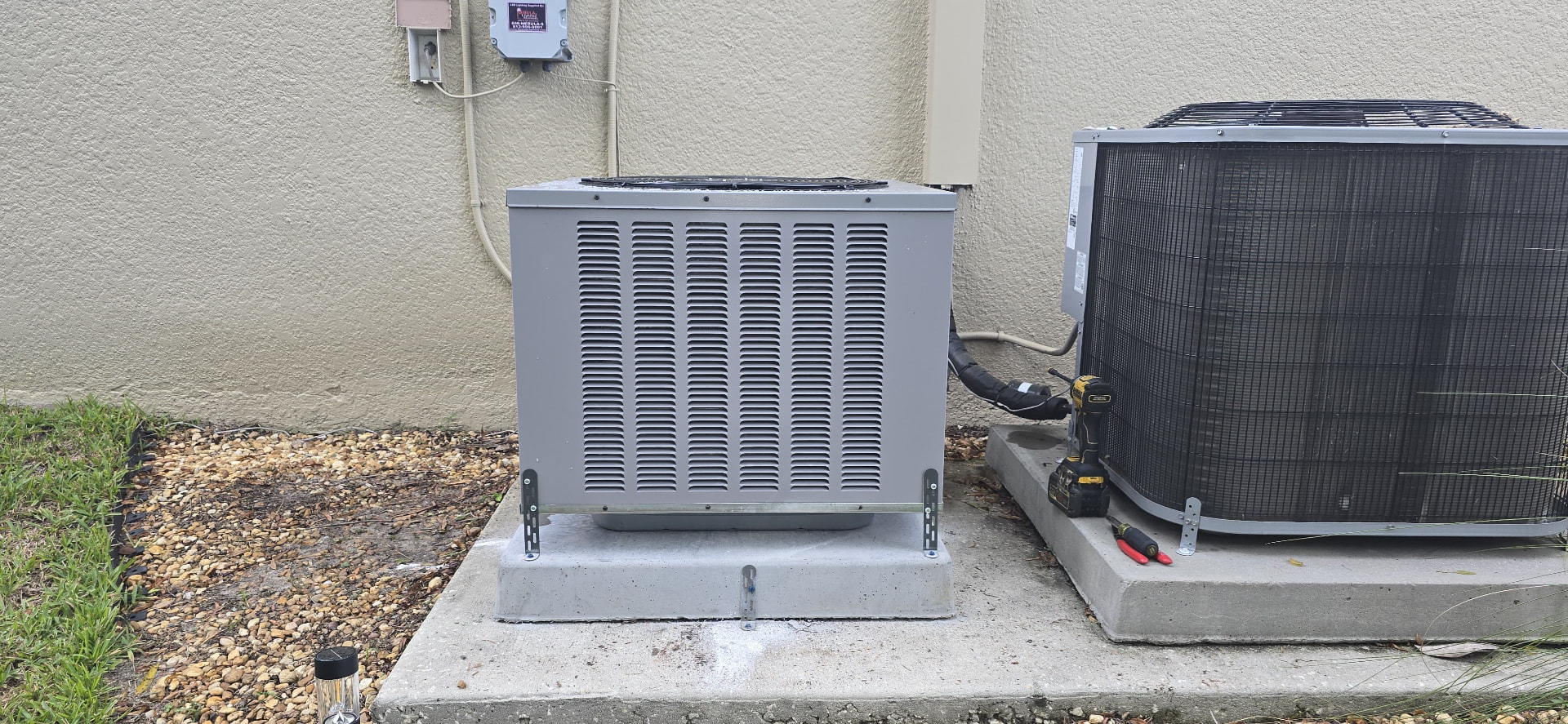 Two new condensers set on concrete slabs outside a home