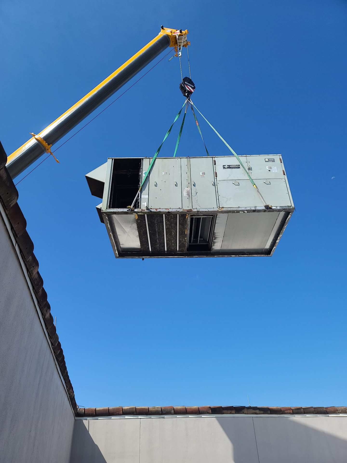 Crane lifting a commercial rooftop unit during a change out